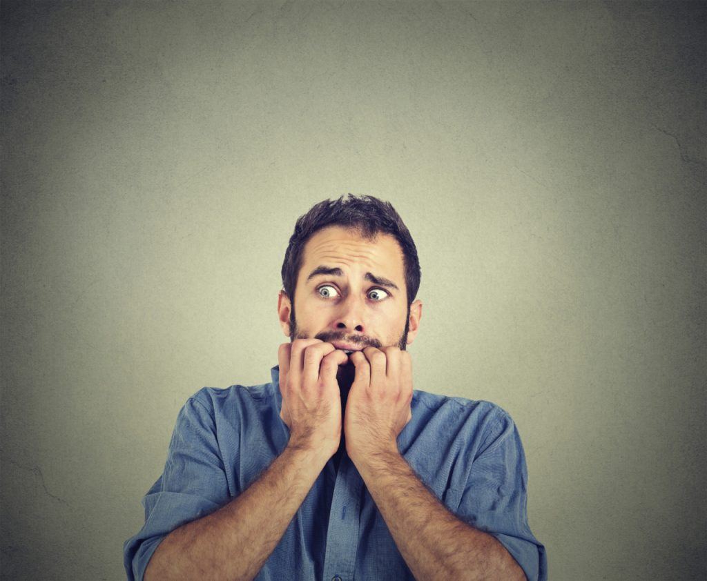 Man with his hands to his mouth biting his nails (MODEL)