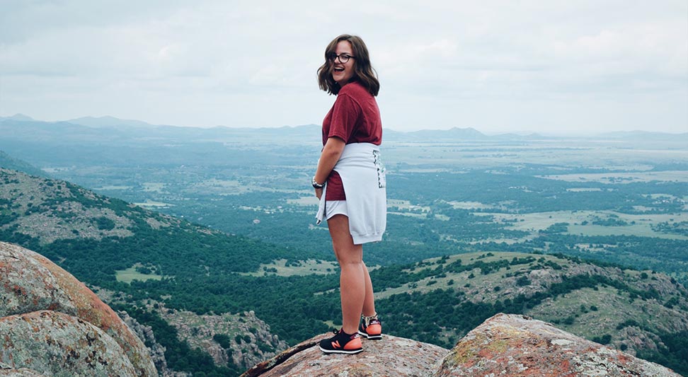nJoy Vision Summertime is LASIK blog post story image of a young lady standing at the top of Mt. Scott in Oklahoma
