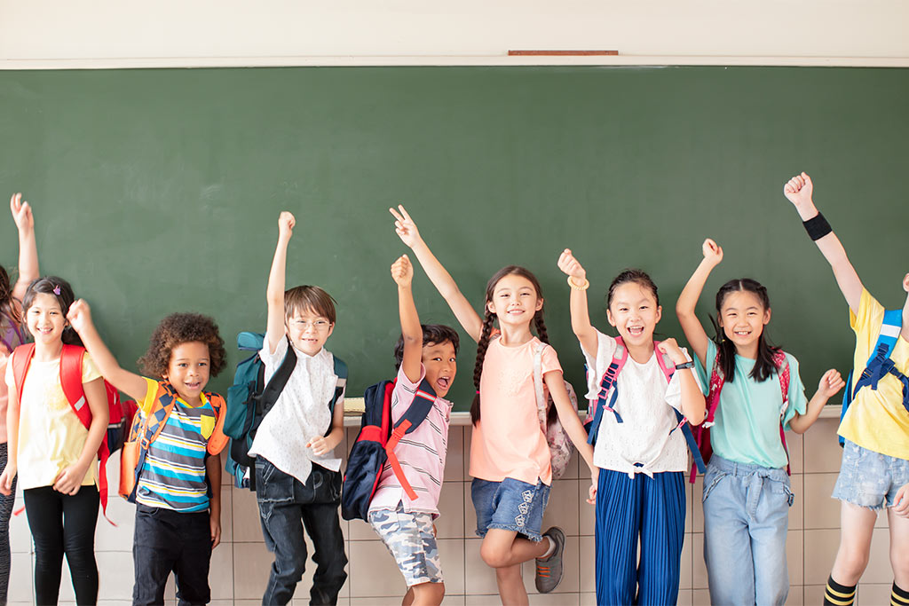 nJoy Vision Children's Eye Health and Safety Month blog post feature image of happy school-aged children in front of a chalkboard