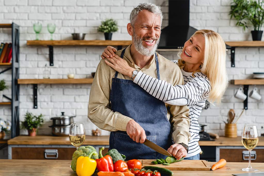 nJoy Vision Healthy Aging Month blog feature image of happy older couple preparing dinner in the kitchen